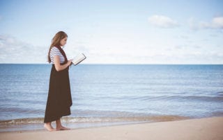 Ermutigungen. Frau liest am Strand