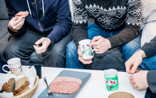 Freiheitsgruppe. Männer sitzen um Couchtisch beim Essen