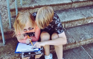 Lehrer. Kinder sitzen auf Stufe und lesen.