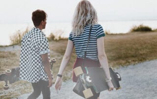 Frauen. Mann und Frau mit Skateboard in der Hand unterwegs.